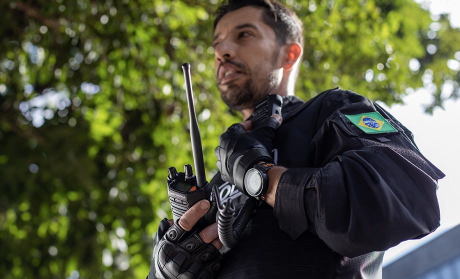 Image of male police officer handling a 2 way radio and advertisement to announce q2 2025 earnings
